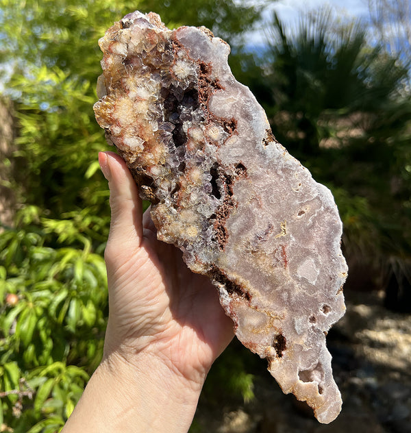 Image of a hand holding a pink amethyst crystal slab.