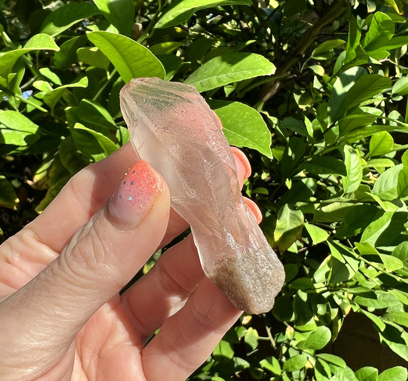 Image of a hand holding a lemurian quartz crystal root. 