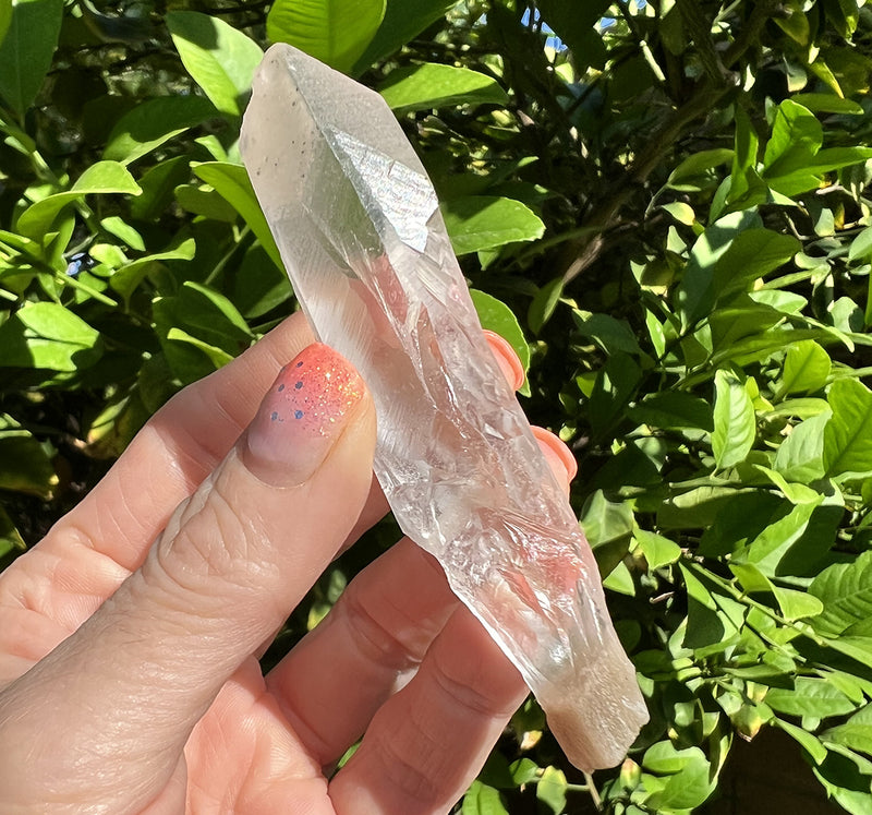 Image of a hand holding a lemurian quartz crystal root. 