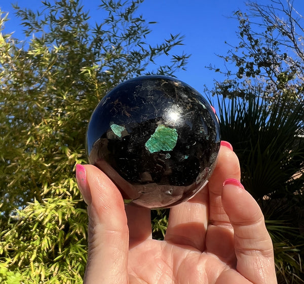 Image of a hand holding aBlack Tourmaline with Chyrsocolla Sphere.