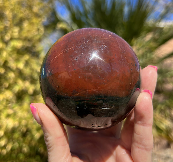 Image of a hand holding a jasper crystal sphere.