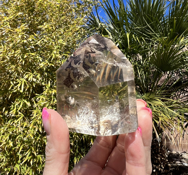 Image of a hand holding a smoky citrine tower. 